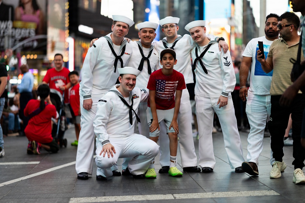 U.S. Navy Sailors pose with a civilian for a photo in Times Square in New York during International Naval Review