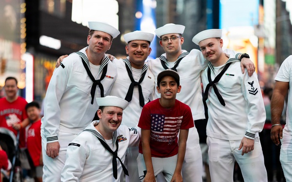 U.S. Navy Sailors pose with a civilian for a photo in Times Square in New York during International Naval Review