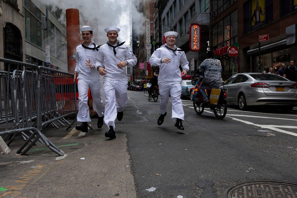 .S. Navy Sailors run near Times Square in New York while celebrating International Naval Review