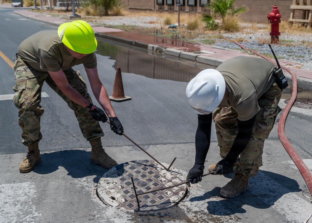 Cable specialists conduct maintenance hole inspection to support base operations
