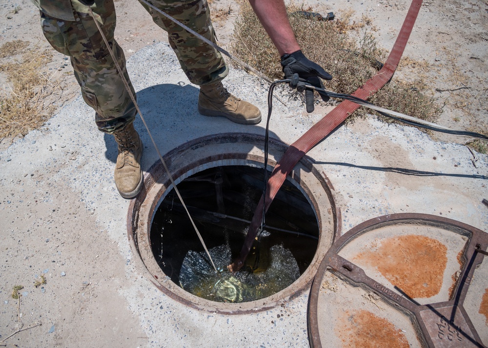 Cable specialists conduct maintenance hole inspection to support base operations