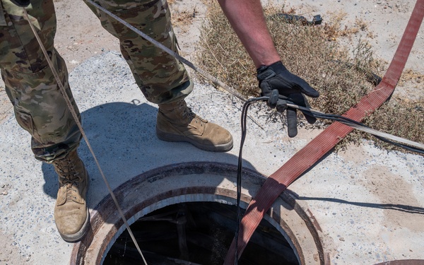 Cable specialists conduct maintenance hole inspection to support base operations