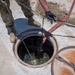 Cable specialists conduct maintenance hole inspection to support base operations