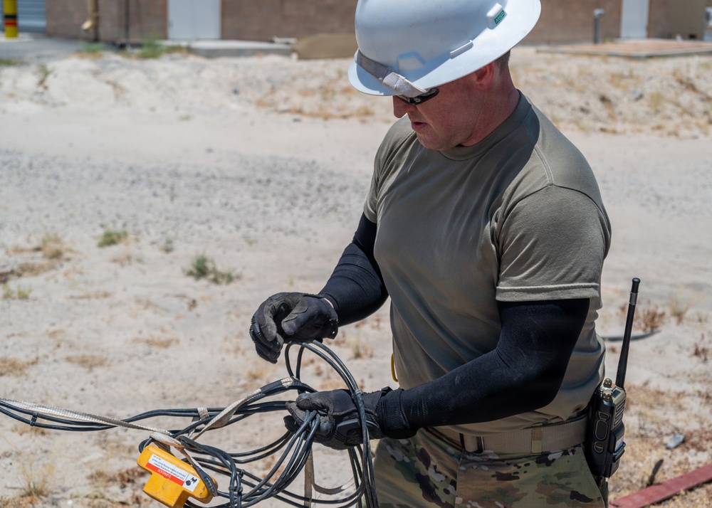 Cable specialists conduct maintenance hole inspection to support base operations