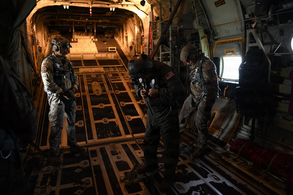Military personnel conduct pre-jump equipment checks aboard military cargo aircraft