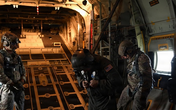 Military personnel conduct pre-jump equipment checks aboard military cargo aircraft