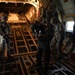 Military personnel conduct pre-jump equipment checks aboard military cargo aircraft