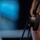 A close-up photograph of a person wearing a Plantronics brand headset on their right ear. The image is taken from behind and slightly to the side, with a blurred blue background suggesting a monitor or screen in the foreground. The focus is sharp on the headset and ear, emphasizing the professional audio equipment.