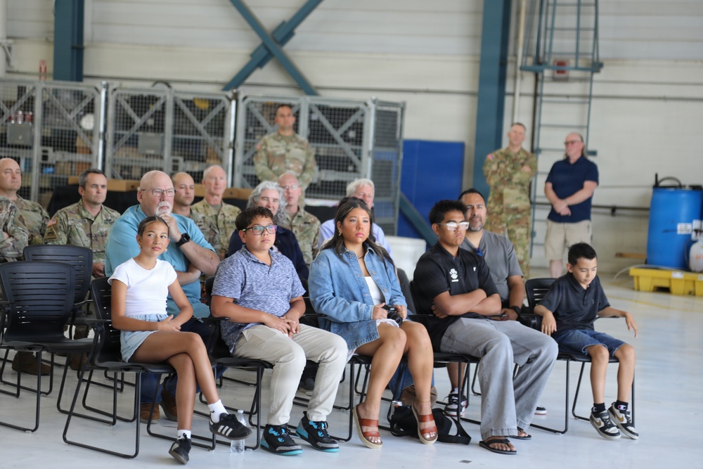 Family members and military personnel attend ceremony inside aircraft hangar