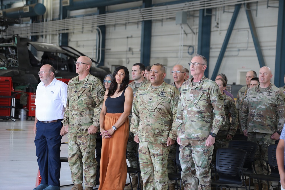 U.S. Army soldiers and civilians stand at attention during a ceremony inside a military aviation hangar