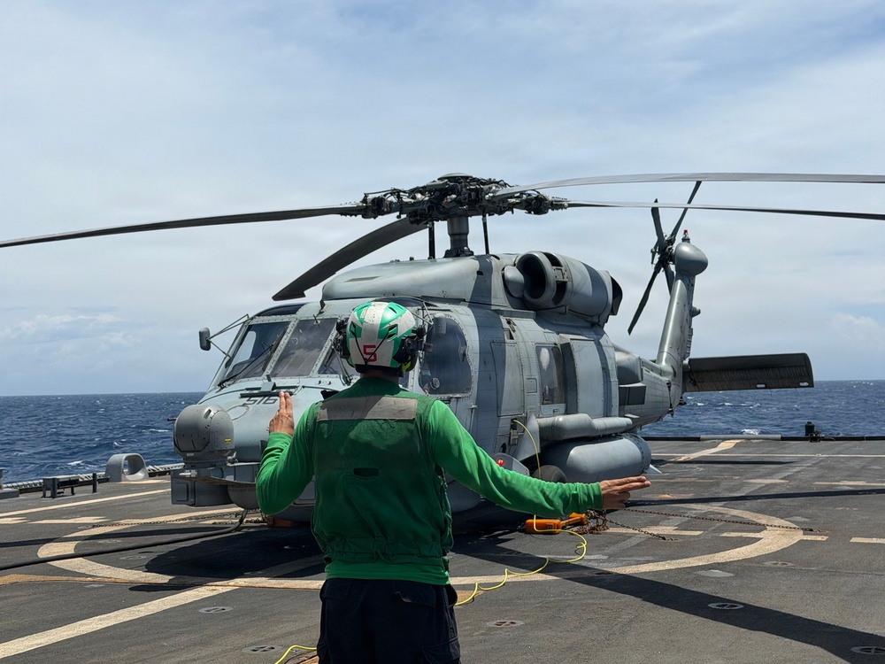 A U.S. Sailor signals an MH-60R Seahawk helicopter, assigned to Helicopter Maritime Strike Squadron (HSM) 48, as part of pre-flight checks aboard the littoral combat ship USS Billings (LCS 15).