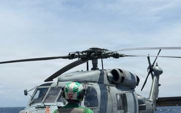 A U.S. Sailor signals an MH-60R Seahawk helicopter, assigned to Helicopter Maritime Strike Squadron (HSM) 48, as part of pre-flight checks aboard the littoral combat ship USS Billings (LCS 15).