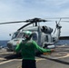 A U.S. Sailor signals an MH-60R Seahawk helicopter, assigned to Helicopter Maritime Strike Squadron (HSM) 48, as part of pre-flight checks aboard the littoral combat ship USS Billings (LCS 15).