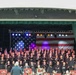 Military Choir and Band Perform Patriotic Concert Before Large American Flag Backdrop