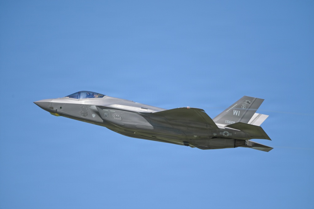 A U.S. Air Force F-35A Lightning II stealth fighter jet is captured in level flight against a clear blue sky. The aircraft bears the tail code 'WI' indicating assignment to a Wisconsin Air National Guard unit, with a visible serial number '5629'. The image is a high-quality side-profile photograph showing significant detail of the aircraft's stealth airframe design.