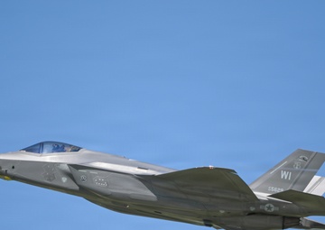 A U.S. Air Force F-35A Lightning II stealth fighter jet is captured in level flight against a clear blue sky. The aircraft bears the tail code 'WI' indicating assignment to a Wisconsin Air National Guard unit, with a visible serial number '5629'. The image is a high-quality side-profile photograph showing significant detail of the aircraft's stealth airframe design.