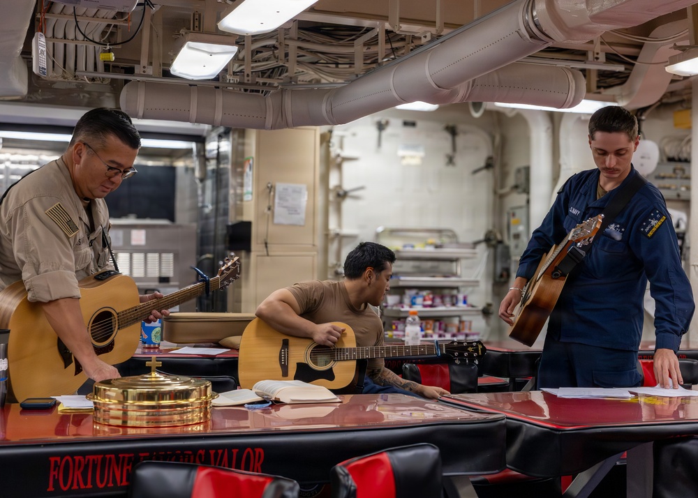 Navy sailors practice guitar during a protestant divine service