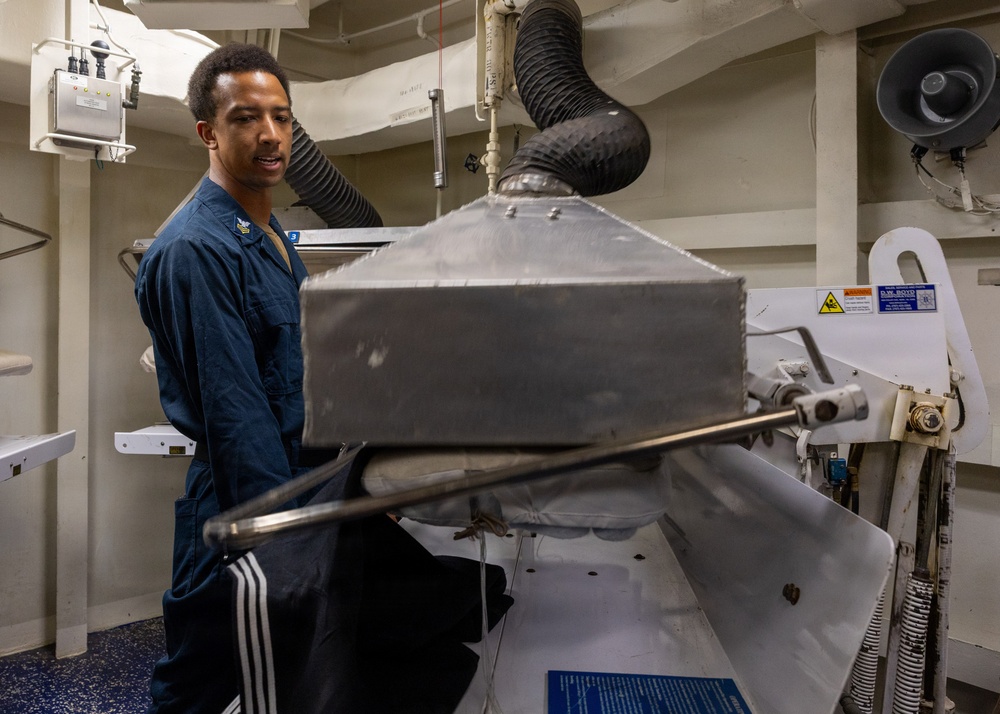 U.S. Navy Sailor Operates Laundry Equipment Aboard Naval Vessel