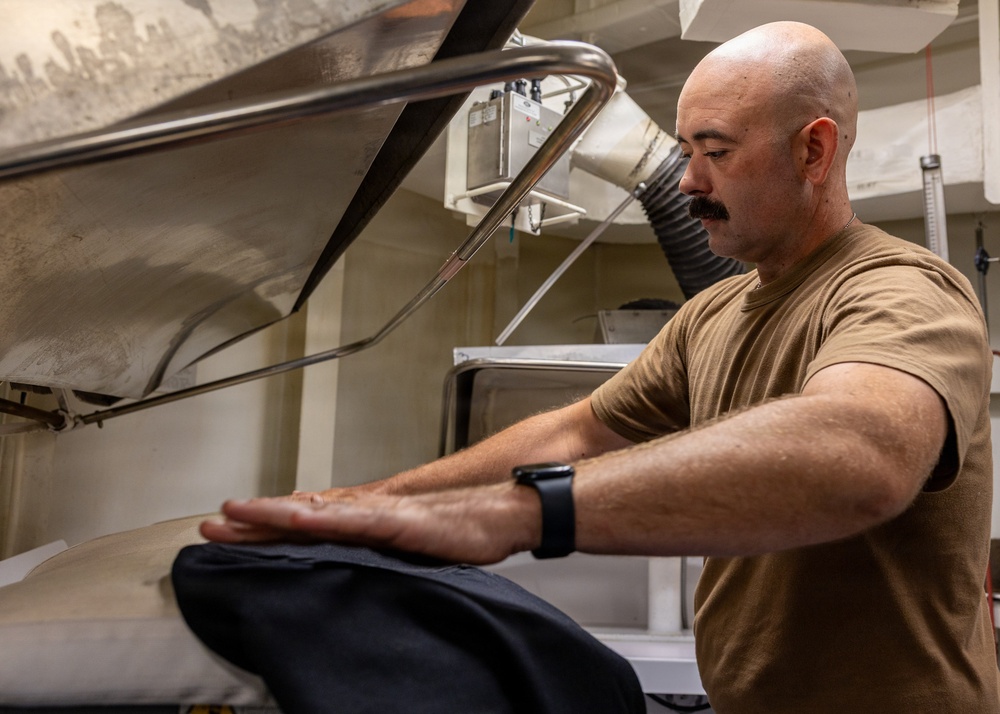 Sailor Operates Laundry Equipment Aboard Naval Vessel