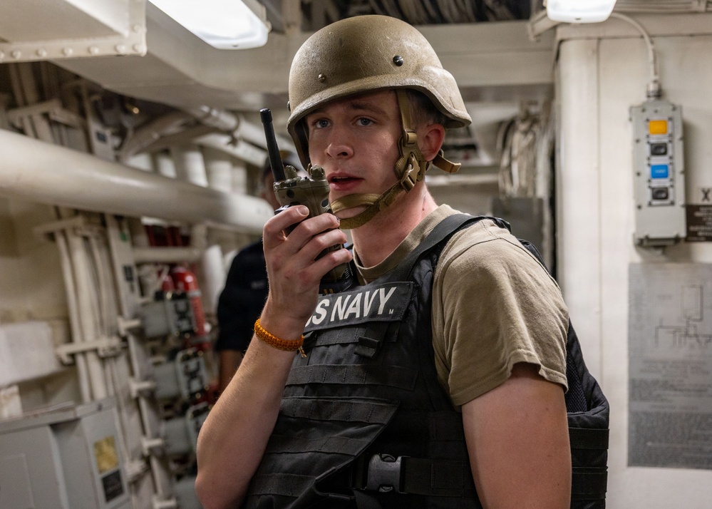 U.S. Navy Sailor Communicates via Radio Aboard Naval Vessel During Operations