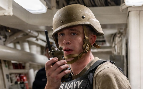 U.S. Navy Sailor Communicates via Radio Aboard Naval Vessel During Operations
