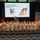 A large group of ROTC or JROTC cadets in camouflage uniforms poses for a group photo in an auditorium. Behind them, a projection screen displays information about Colonel Clifton M. Bell, Commander of the 412th Operations Group at Edwards Air Force Base, California. Two individuals in non-camouflage attire stand elevated on the stage behind the group.