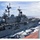 A large U.S. Navy amphibious assault ship bearing the hull number '2' is underway at sea, photographed from the deck of an adjacent vessel during what appears to be an underway replenishment (UNREP) operation. The ship displays a flat flight deck with rotary-wing aircraft visible on the stern, multiple radar and communications masts, and transfer lines connecting it to the observing vessel. The sea conditions are moderate with blue water and partial cloud cover.