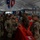 JTF-DC guardsmen prepare for patrol A group of U.S. Army soldiers in OCP (Operational Camouflage Pattern) uniforms are gathered inside a large tent or temporary structure. They appear to be at a staging or coordination area, congregating around orange plastic water-filled barriers. State flags are visible hanging from the tent ceiling, suggesting a multi-state National Guard or joint military operation.