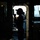 Routine Operations Aboard USS Mason (DDG 87) A silhouetted figure stands in a doorway or hatchway aboard what appears to be a naval or military vessel, backlit by an overcast sky outside. The person is wearing a cap and appears to be holding a communication device or radio to their face. The image is a dramatic high-contrast silhouette photograph taken from inside the ship's interior.