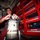 Routine Operations Aboard USS Mason (DDG 87) A young man in a red uniform is working with a Scott Safety SCBA (Self-Contained Breathing Apparatus) cylinder, appearing to inspect or connect the regulator valve. The setting appears to be inside a fire truck or emergency response vehicle, evidenced by the red tool storage cabinets with labeled drawers in the background. The environment is consistent with firefighting or emergency services equipment maintenance.