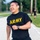 2026 Paralegal Warrior A person wearing a black 'ARMY' t-shirt is running and laughing with visible joy and exertion. The setting appears to be a military base or installation road, with other individuals visible in the background. The image captures an energetic, positive moment during what appears to be a physical training exercise.