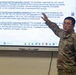 A US Army soldier in OCP (Operational Camouflage Pattern) uniform is presenting a briefing in front of a large interactive display screen. The presentation appears to cover legal and administrative topics related to military separation packets, JAG oversight, and paralegal responsibilities. The setting appears to be a classroom or training room environment.