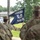 2026 Paralegal Warrior A group of military personnel in U.S. Army OCP (Operational Camouflage Pattern) uniforms are gathered at what appears to be an outdoor ceremony. A soldier identified by nametape as 'RODRIGUEZ' is holding a dark navy blue guidon flag reading 'PARALEGAL WARRIORS' with a crossed-quill-and-sword emblem. The scene suggests a unit formation, activation, or recognition ceremony.