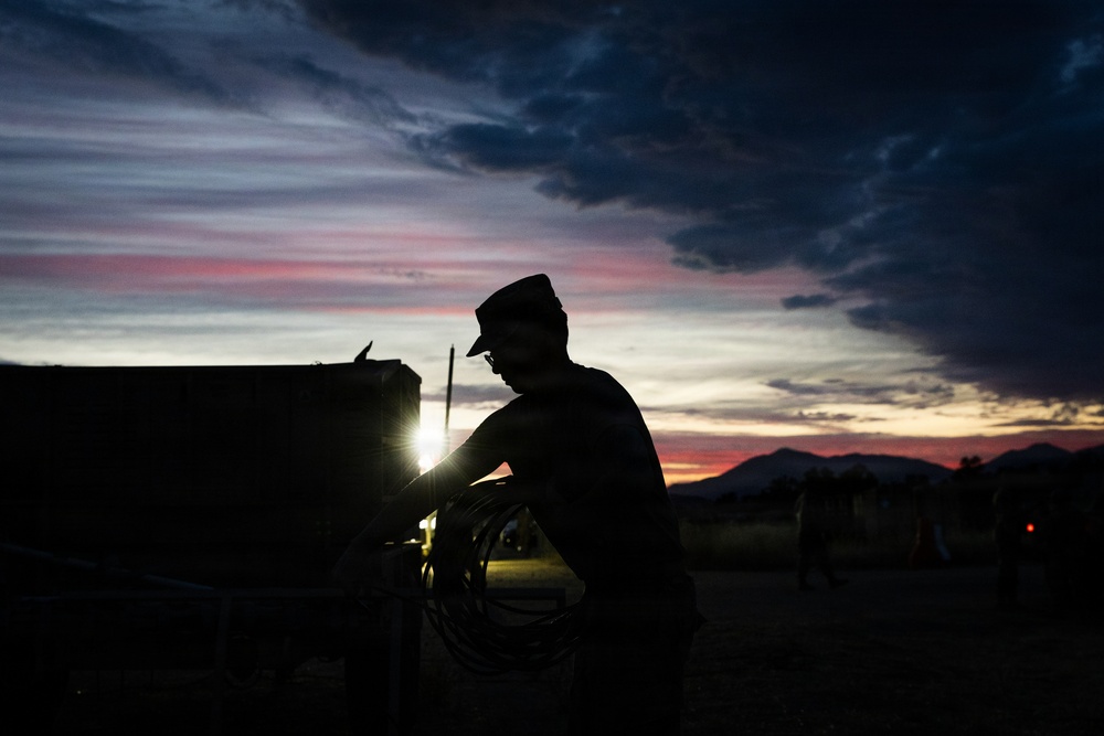 Soldier silhouetted against sunset sky during field operations
