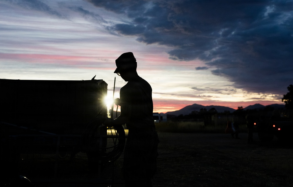 Soldier silhouetted against sunset sky during field operations