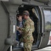 A military service member in OCP (Operational Camouflage Pattern) uniform is speaking with a civilian visitor seated inside a military medical helicopter, identifiable by the red cross markings on its fuselage. The interaction appears to be an informational tour or demonstration, likely at a public event or open house. The helicopter is a UH-60 Black Hawk configured for medevac/CASEVAC operations.