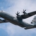 A U.S. Air Force C-130 Hercules military transport aircraft is photographed in flight against a partly cloudy blue sky. The aircraft belongs to the West Virginia Air National Guard, as indicated by markings on the fuselage and tail. The aircraft is captured from a low angle, showing its underside and four turboprop engines.