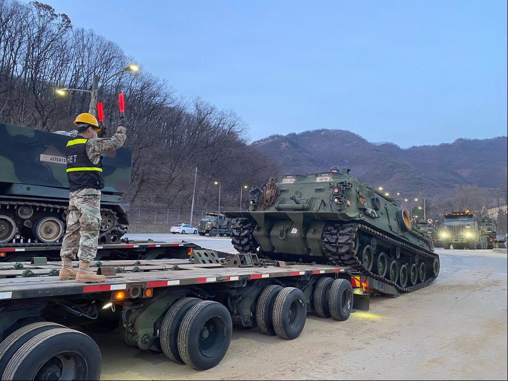 Heavy equipment transporter loads armored recovery vehicle