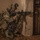 A U.S. Army soldier identified by the name tape 'REYES' is crouched in a tactical position against a wall, aiming an M4-style carbine rifle around a corner toward a metal gate. The soldier is wearing full combat gear including MultiCam camouflage, a helmet with night vision device mounted, body armor, and a full rucksack. A camera is also visible hanging from the soldier's kit, suggesting a possible combat documentation or media role.