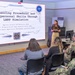 A presenter is delivering a briefing titled 'Enhancing Procedural and Interpersonal Skills Through LARP Simulation' to a small audience in a conference room. The presentation is associated with Applied Science and Analytics (ASA), the Dr. Richard Oliver Hope Research Center (HRC), and the Defense Equal Opportunity Management Institute (DEOMI). The audience includes both military personnel in uniform and civilians.