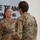 USARIEM COC/Relinquishment of Responsibility 2026 Two U.S. Army soldiers in OCP (Operational Camouflage Pattern) uniforms are engaged in a face-to-face conversation in what appears to be a military facility. The soldier facing the camera, identified by the name tape 'ROSSER,' is wearing a colonel's eagle insignia and a medal on her chest, suggesting a recent award ceremony. A motivational wall display reading 'ONE TEAM ADVANCING INNOVATIVE TECHNOLOGY' is visible in the background.
