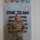 USARIEM COC/Relinquishment of Responsibility 2026 A U.S. Army female officer in OCP (Operational Camouflage Pattern) uniform stands before a wall display reading 'ONE TEAM ADVANCING INNOVATIVE TECHNOLOGY FOR & TOMORROW' with military branch seals above it. She is holding what appears to be an award plaque and is wearing a medal on her chest, suggesting this is an award or recognition ceremony. Her name tape reads 'ROBBEN' and she wears a Colonel's eagle rank insignia.