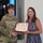 USARIEM COC/Relinquishment of Responsibility 2026 A U.S. Army Brigadier General (one star, name tag reading 'JENKINS') is presenting a Certificate of Appreciation to a civilian woman identified on the certificate as 'Mrs. Melissa J. Marconi'. Both individuals are holding the framed certificate and shaking hands in what appears to be an official military ceremony. The setting appears to be an indoor facility with a display screen visible in the background.