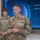 USARIEM COC/Relinquishment of Responsibility 2026 A U.S. Army Sergeant Major (name tag reads 'MARCONI') is speaking at what appears to be an awards ceremony, wearing a medal on his chest consistent with the Legion of Merit or Meritorious Service Medal. Several other uniformed Army personnel are visible in the background, along with a large digital display screen showing a globe graphic with labels 'Detectability' and 'Susceptibility'. The setting appears to be a modern military briefing or operations room.