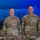 USARIEM COC/Relinquishment of Responsibility 2026 Two U.S. Army soldiers in OCP (Operational Camouflage Pattern) uniforms are posing together, both wearing medals on their chests, suggesting a military awards ceremony. The name tapes visible read 'ROSSER' on the left (female soldier with Colonel rank insignia) and 'MARCONI' on the right (male soldier with Sergeant Major rank insignia). A civilian woman is partially visible on the right edge of the frame.