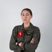 A formal portrait of a U.S. Marine Corps officer in an olive drab flight suit, standing with arms crossed against a neutral gray background. The subject wears squadron patch 'HMH-465 Warhorse' on the left chest and a naval aviator wings badge on the right chest. Name tape reads 'REED' with rank 'CAPT' and branch 'USMC' visible.