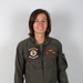 A person wearing an olive green military flight suit stands against a neutral gray background in what appears to be an official portrait photograph. The flight suit displays a squadron patch reading 'Death Rattlers VMFA-323' and a name tag reading 'L.N. Modica, CAPT, USMC' with naval aviator wings. The subject is smiling and facing the camera directly.