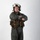 MCAS Marines pose for content 2026 A military aviator stands in a full-body portrait pose against a white studio background with arms crossed. The individual is wearing a flight suit with survival/tactical gear and a white flight helmet. The image appears to be a professional or official-style portrait photograph.