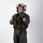 MCAS Marines pose for content 2026 A military aviator stands in a full flight suit ensemble against a plain white studio background. The individual is wearing complete flight gear including a helmet, survival vest, harness, and gloves, posed in a formal standing position. The image appears to be a professional or official documentation photograph.