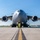 A large military transport aircraft, identified as a C-17 Globemaster III, is photographed head-on from ground level on a tarmac. The aircraft bears the tail number 0094 and markings consistent with the 445th Airlift Wing. Ground support equipment is visible beneath the nose, and the image captures all four turbofan engines prominently.